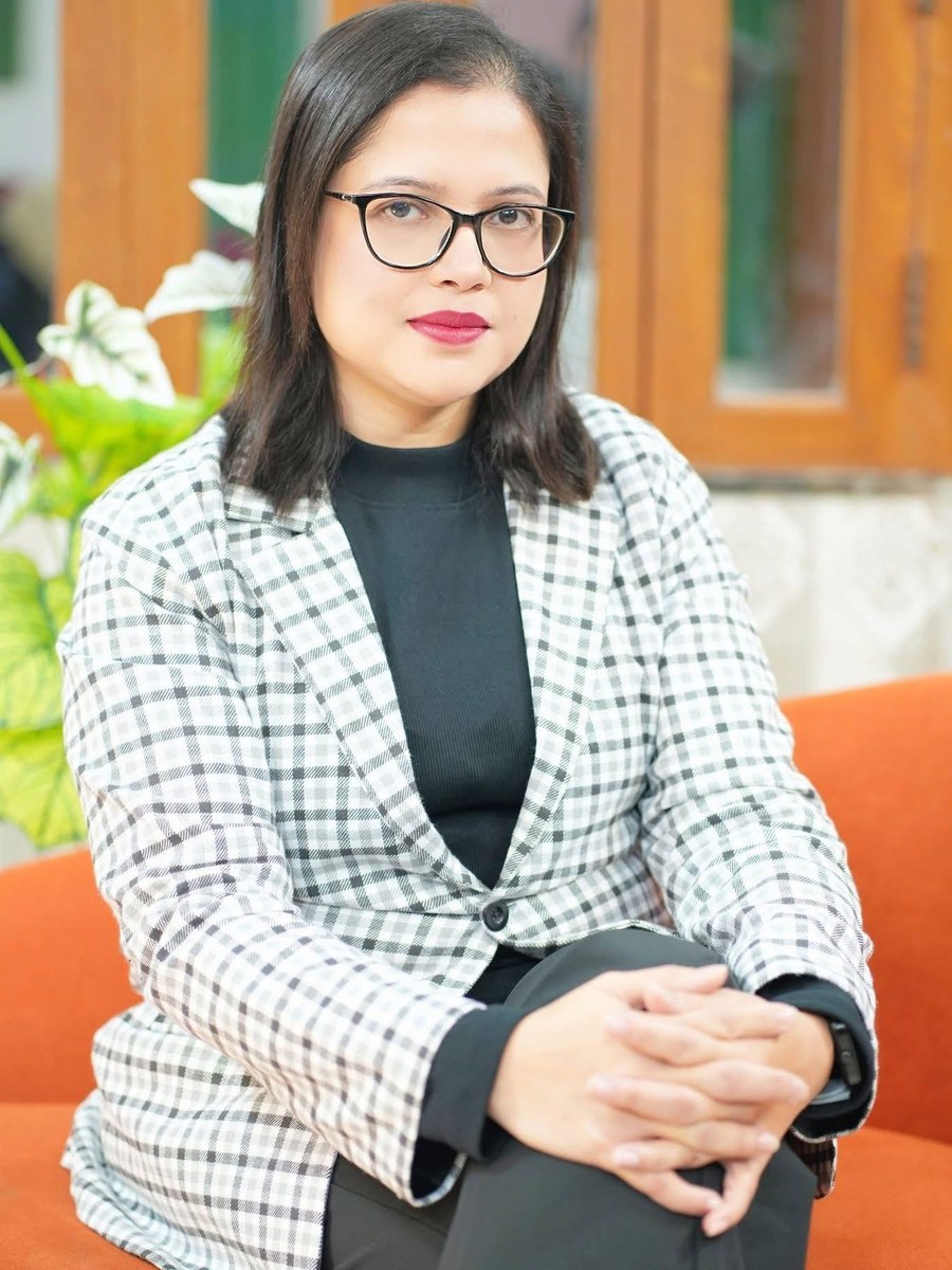 Dr. Sifat-E-Aman seated, in a checked blazer and glasses, hands folded.